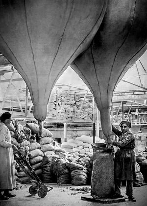 Black and white photo of two women filling bags of asbestos in a factory