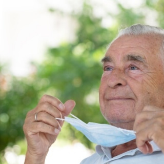 Older man taking off medical mask