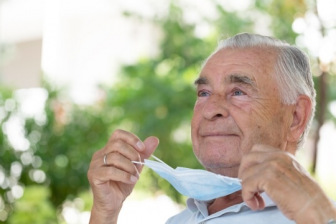 Older man taking off medical mask