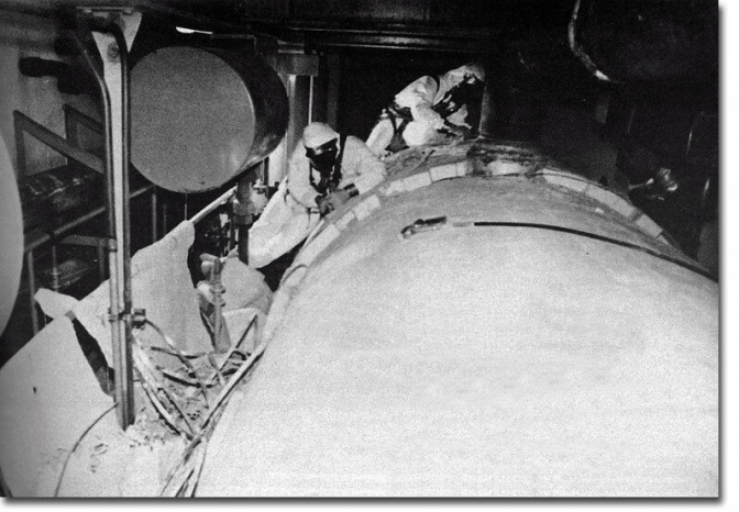 Black & white image from a vintage asbestos abatement industry publication showing asbestos abatement workers removing asbestos tank insulation.