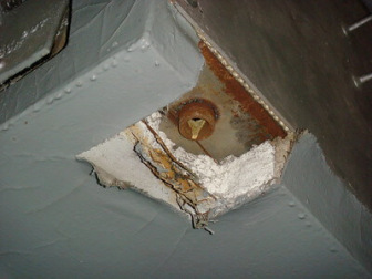 Small localized area of exposed asbestos magnesia boiler block insulation apparently previously cut away for access to coupling.