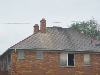Decades-old asbestos roof shingles have outlasted the boarded-up house and its occupants.
