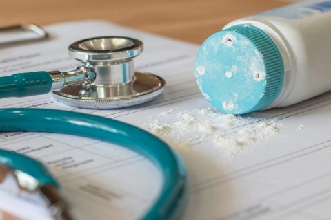 Baby powder product with talc mineral spilling over diagnosis record paper on doctor's pad - Copy