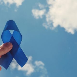 Man holding blue ribbon up to the sky