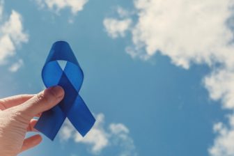 Man holding blue ribbon up to the sky