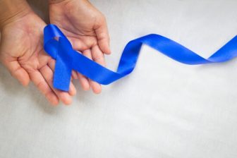 Blue cancer awareness ribbon with hands