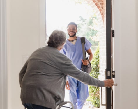 Woman opening door for doctor house visit