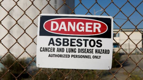 Danger asbestos sign on fence at plant