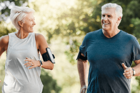 Elderly couple enjoys being active together by running through nature