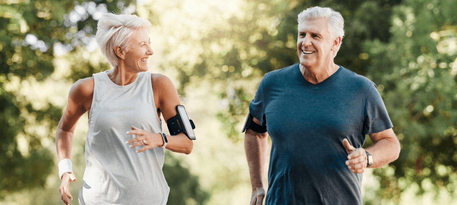 Elderly couple enjoys being active together by running through nature