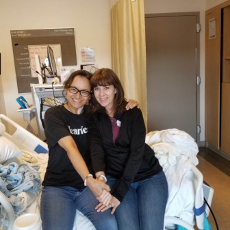 Kim Madril and Jeanette Mednicoff sit on a hospital bed