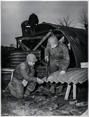 Vintage photo showing US servicemen constructing a hut made with corrugated asbestos sheeting.