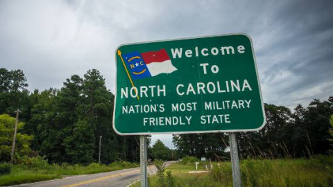 A sign on a two-lane country road welcomes residents and visitors to North Carolina.