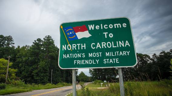 A sign on a two-lane country road welcomes residents and visitors to North Carolina.