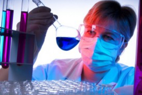 Female researcher examines flask with blue fluid