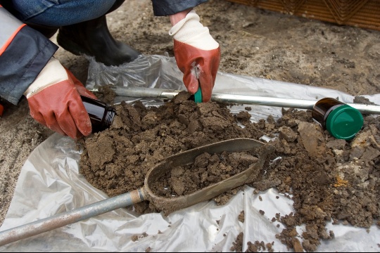 Gloved person with soil samples on tarp