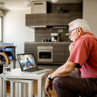 Older man looking at computer with image of doctor