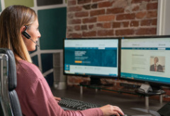 Woman with a headset microphone on looking at computer screens