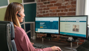 Woman with a headset microphone on looking at computer screens
