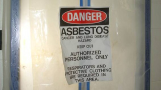 Asbestos danger sign on plastic-covered door