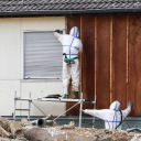 Professionals in protective suits remove asbestos on a wall