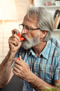 older man using asthma inhaler