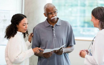 Man with daughter and doctor looking at pamphlet