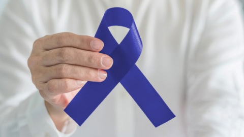 Hand holding blue awareness ribbon