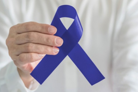 Hand holding blue awareness ribbon