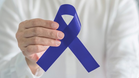 Hand holding blue awareness ribbon