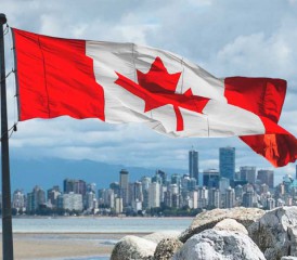 Canadian flag waving over Vancouver skyline