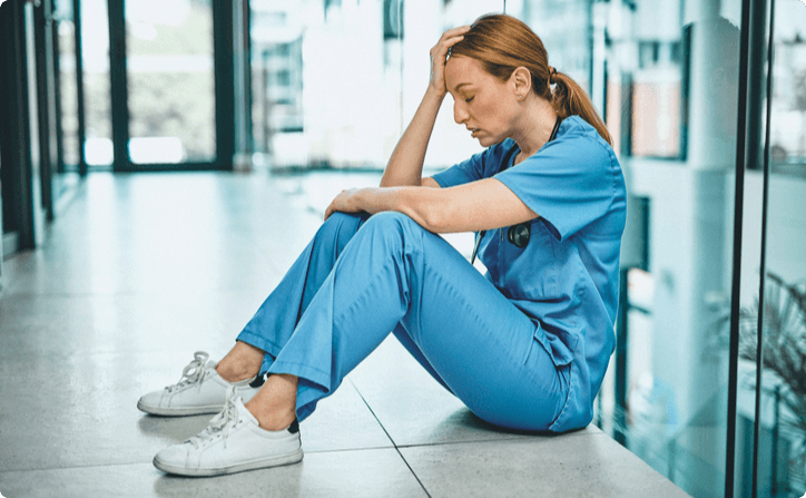 Nurse sitting on the floor, appearing to be tired