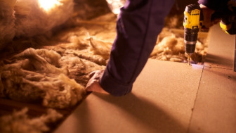 Carpenter in attic with old insulation