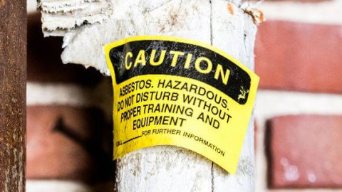 Yellow asbestos caution sign on insulated pipe