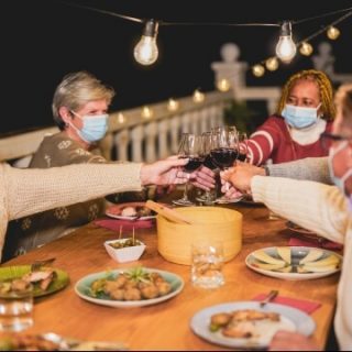 Group with masks toasting over food outdoors