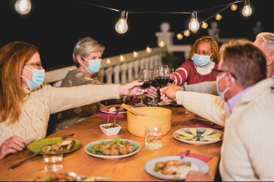 Group with masks toasting over food outdoors