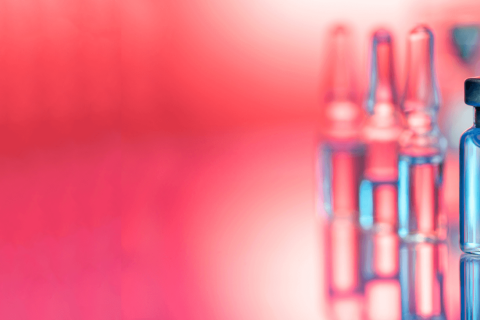 Close up shot of vaccines - glass bottles, ampules and syringe with needle.