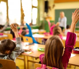Children in a classroom with arms raised