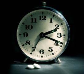 Clock with sleeping pills next to it