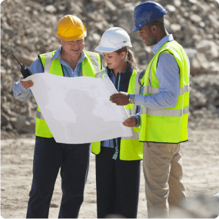 Three construction workers on a job site reviewing plans
