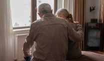 Man comforting woman by a window