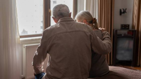 Man comforting woman by a window