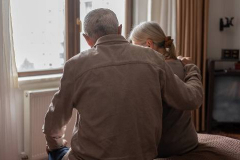 Man comforting woman by a window