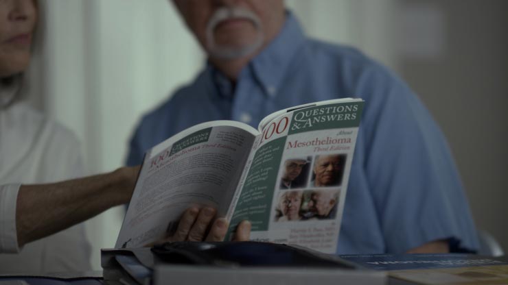 Older man and spouse reading Mesothelioma Q&A book