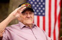 U.S. World War 2 veteran saluting with an American flag in background