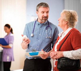 Doctor carrying clipboard talks to patient