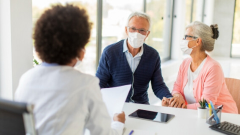 Physician at desk with patient and wife