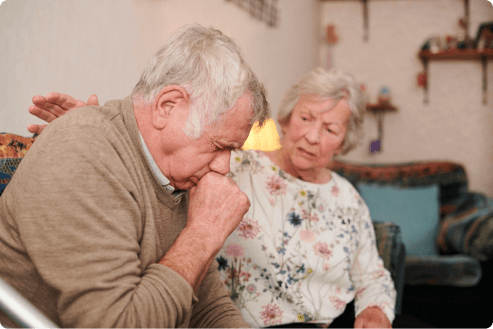 Older woman comforting her husband as he coughs