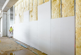 Man installing drywall in a warehouse