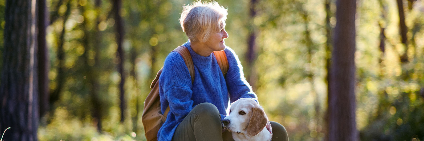 Woman hiking in the woods with dog